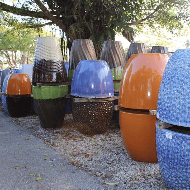 Large ceramic planters in vibrant colors displayed outdoors in a Kendall nursery